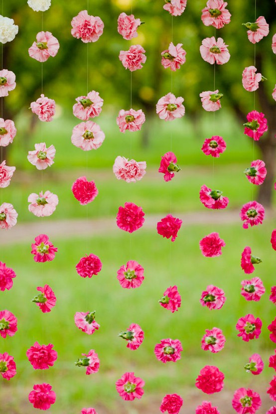 Strands of pink and white flowers hanging vertically against a softly blurred green outdoor background, romantic and warm