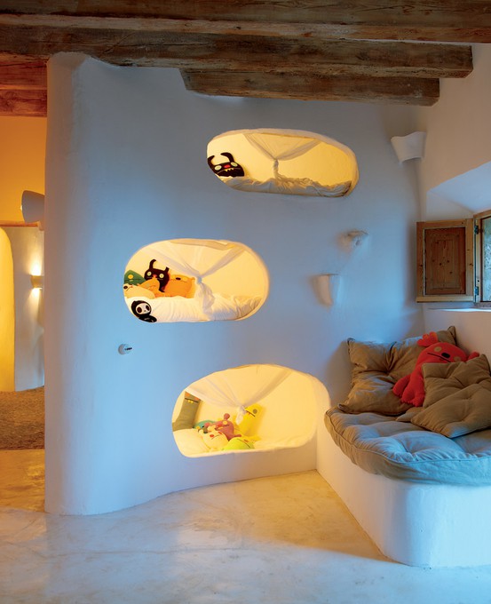 A cozy curved white alcove with warm lighting and soft cushioned seating in white and warm orange tones